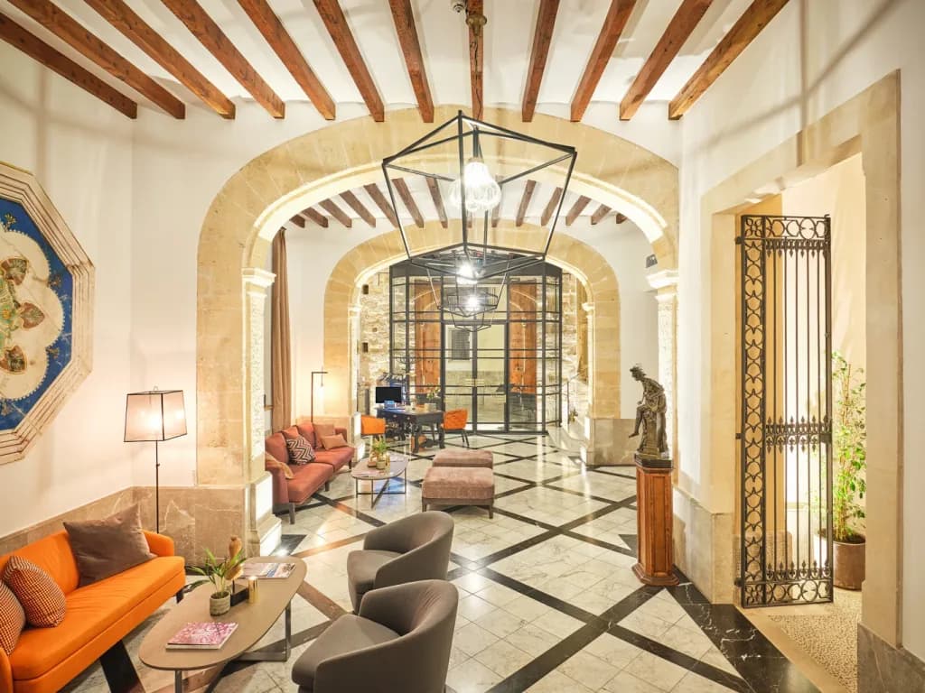 Recibidor de un hotel de Cabau Hotels con arcos de piedra, vigas de madera y suelo de mármol